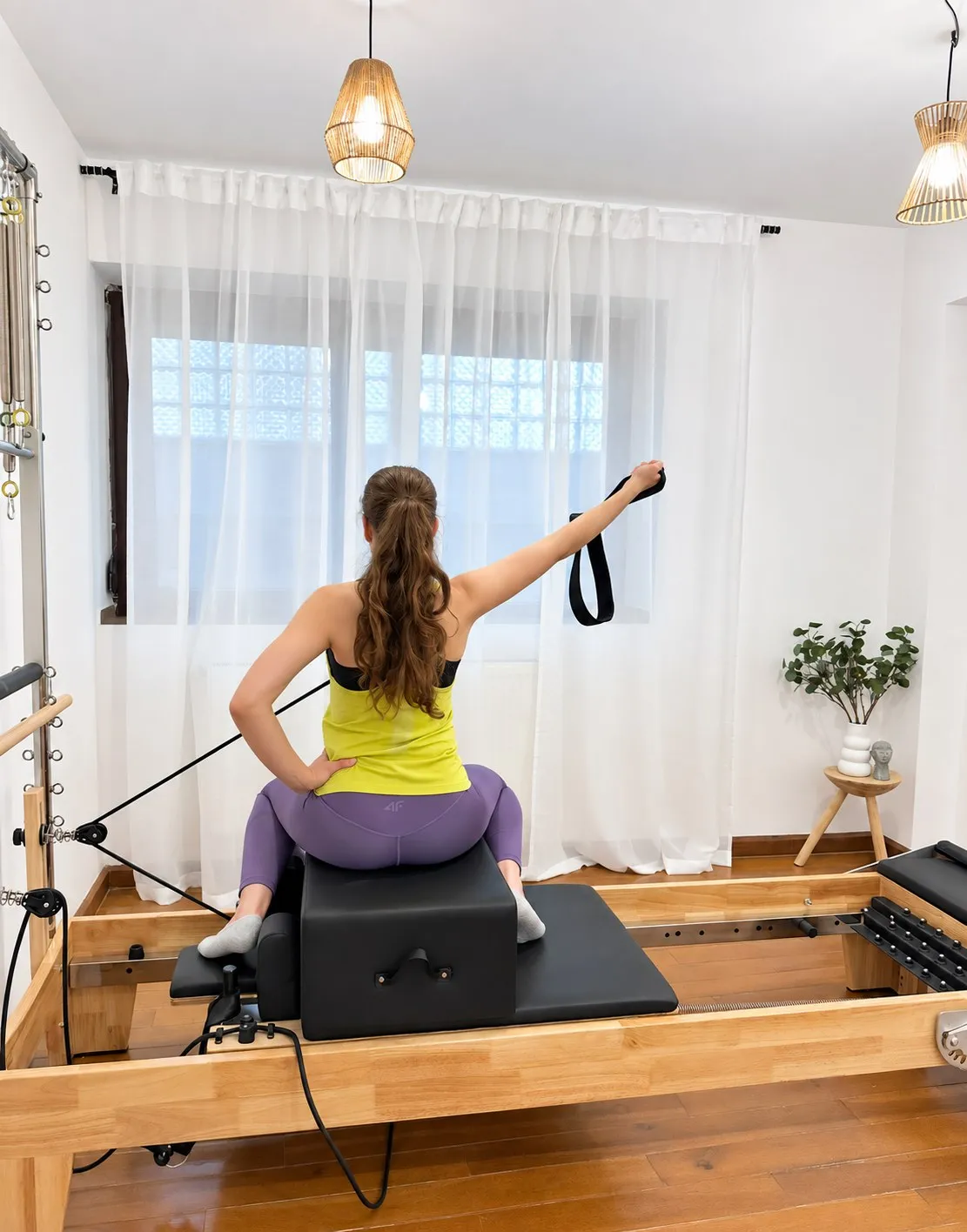 Exercițiu cu chingile pe aparatul Reformer, în studioul Tess Fit